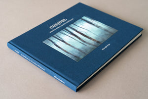 Vedere în perspectivă (unghi tridimensional) a albumului de artă „Cuejdel - A Tale from the Carpathian Wilderness”. Se observă cotorul cărții personalizat cu numele autorului Gheorghe Popa și titlul lucrării, textura premium a pânzei albastre și grosimea paginilor, subliniind calitatea de obiect de colecție.