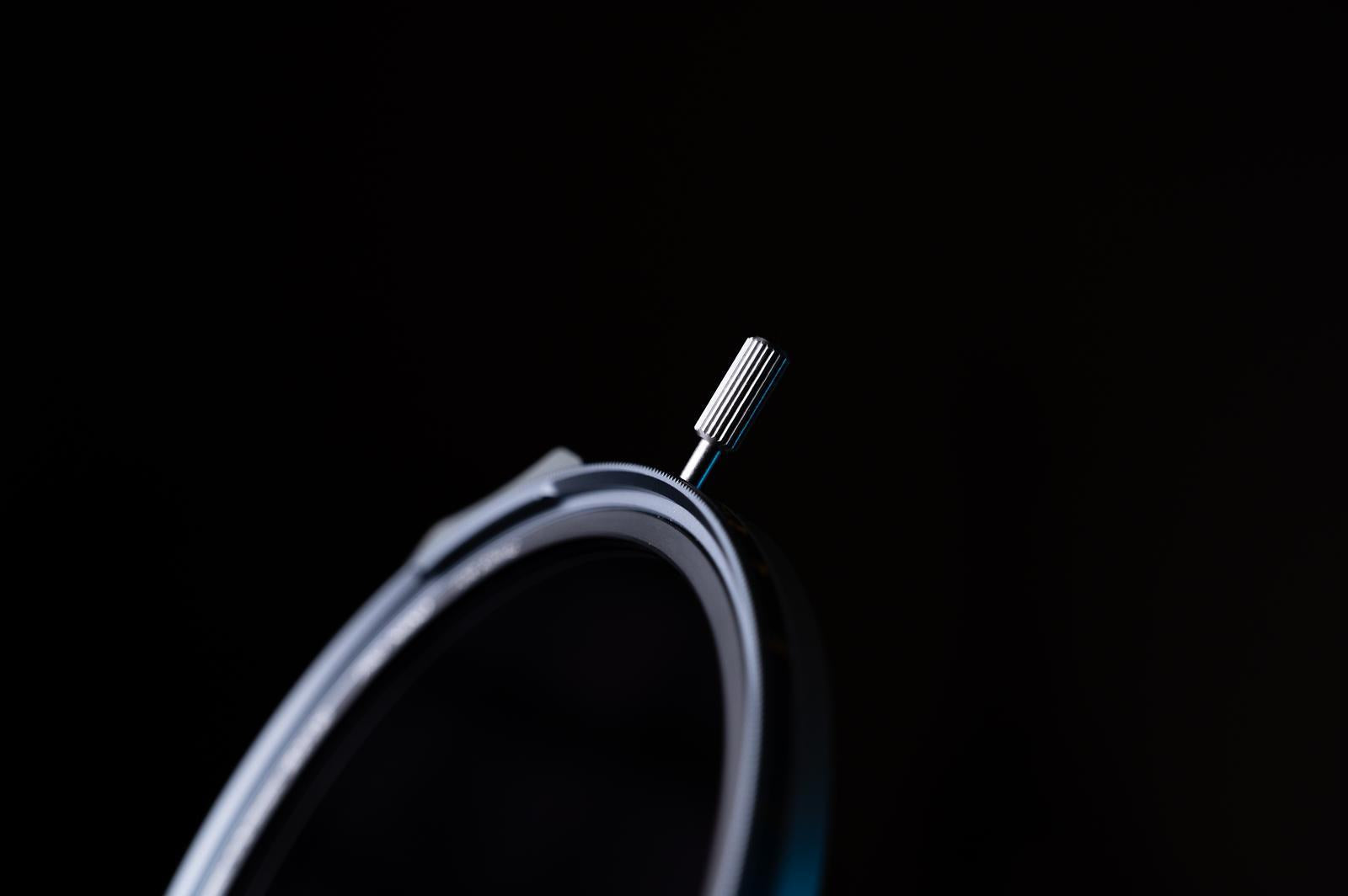 Close-up of a circular metal component with a screw on a black background