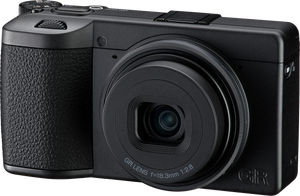 Plan apropiat de înaltă rezoluție al aparatului compact Ricoh GR IV Monochrom, fundal transparent, evidențiind gravura „GR LENS f=18.3mm 1:2.8”, textura grip-ului și designul negru minimalist.