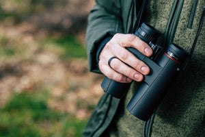Utilizare binoclu Kite Optics Ursus în natură, persoană care ține binoclul de curea în timpul unei drumeții, gphoto.ro