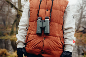 Binoclu Pentax AD 9x28 WP purtat la gât de un drumeț în timpul unei ieșiri în natură