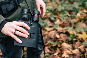 Binoclu cu stabilizare Kite Optics APC 22x50 ED AA ținut în mână de către un utilizator în aer liber