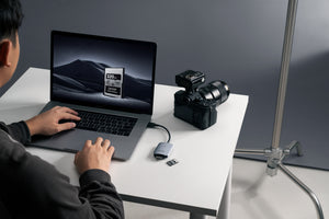 Fotograf utilizând cititorul de carduri Lexar CFexpress Type A LRW515U conectat la un laptop în studio