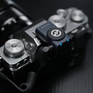 Receptor Hollyland Lark M2 montat pe patina unei camere foto mirrorless, conectat prin cablu TRS, prezentând rotita de control al volumului și indicatorii de stare TX.