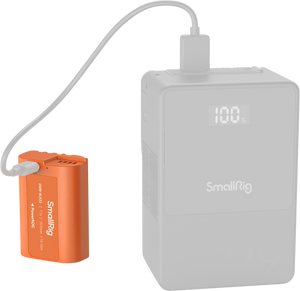 Acumulator SmallRig DMW-BLK22 portocaliu fiind încărcat prin cablu USB de la un power bank extern cu afișaj digital, soluție ideală pentru deplasări.