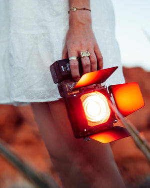 Person holding a light box with a warm glow against a blurred background