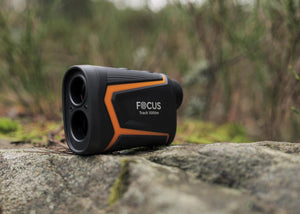 Telemetru laser Focus Track RF 1000m așezat pe o piatră în mediul natural, în timpul unei activități outdoor
